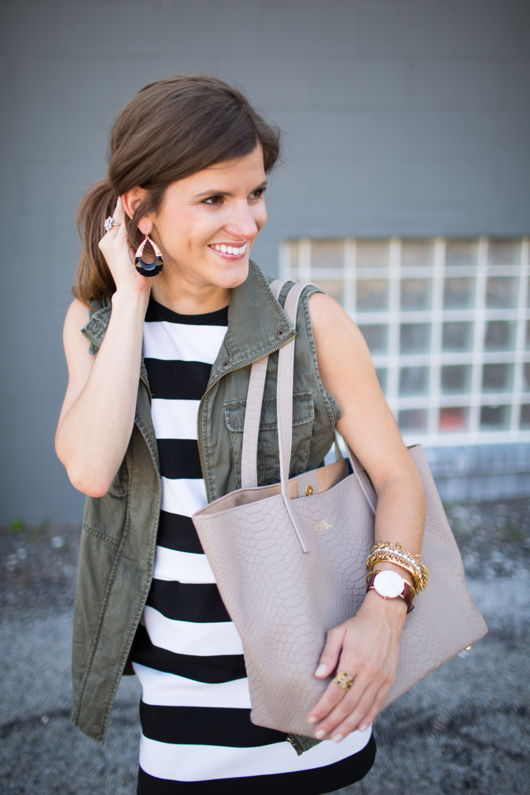 transitional fall outfit idea, olive green utility vest, striped dress, lace up black heels, kendra scott earrings, gigi ny neutral teddy tote, going out outfit, military vest, black and white stripe dress