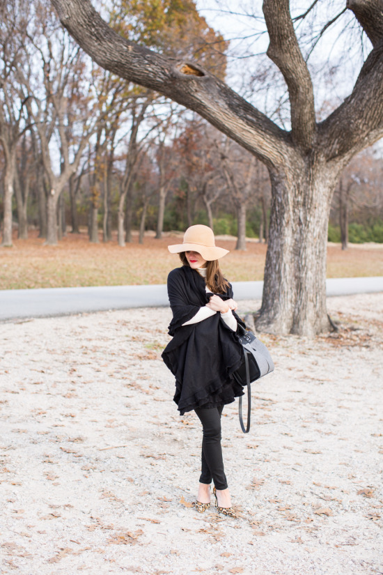 winter outfit with black cape wrap black pants cream turtleneck camel hat and leopard heels
