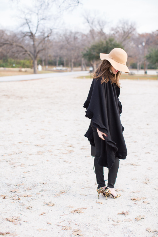 winter outfit with black cape wrap black pants cream turtleneck camel hat and leopard heels