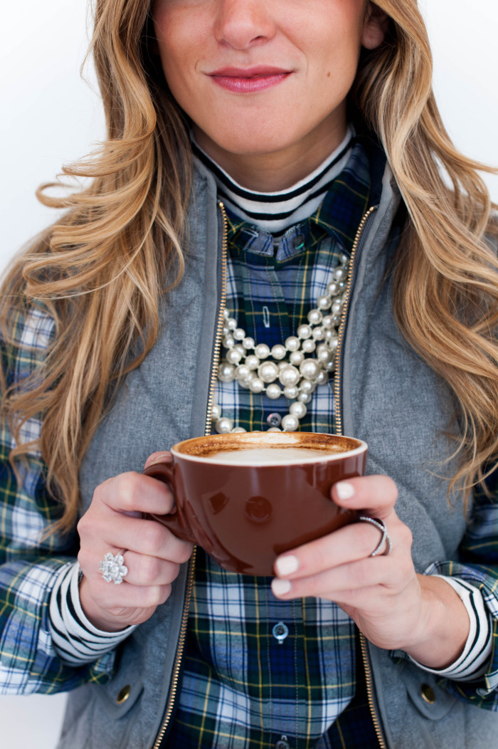 preppy outfit with striped turtleneck and plaid button up and grey puffer vest and pearls and coffee 