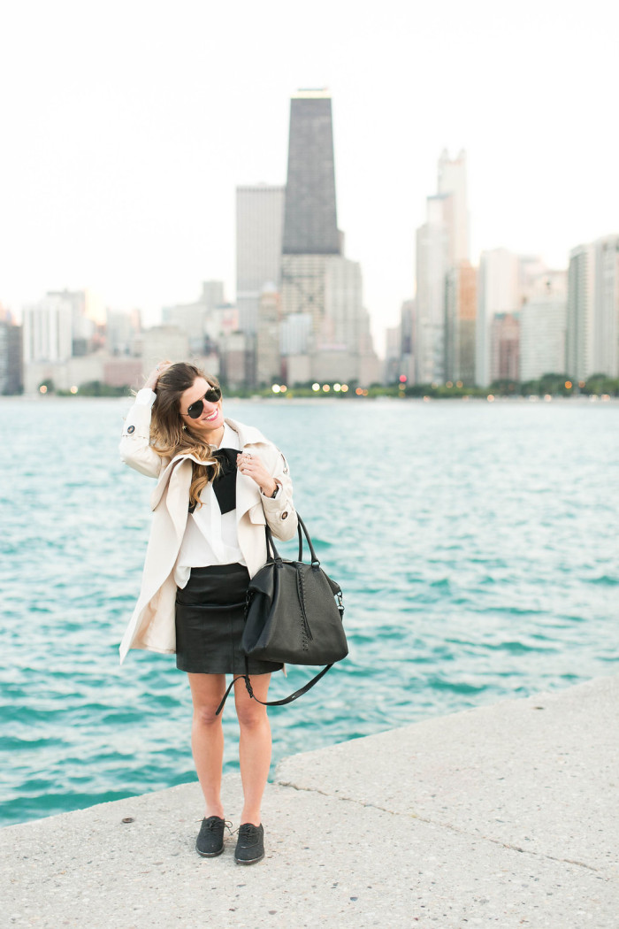 Fall outfit with leather mini skirt and white blouse with bow tie detail and cream trench coat