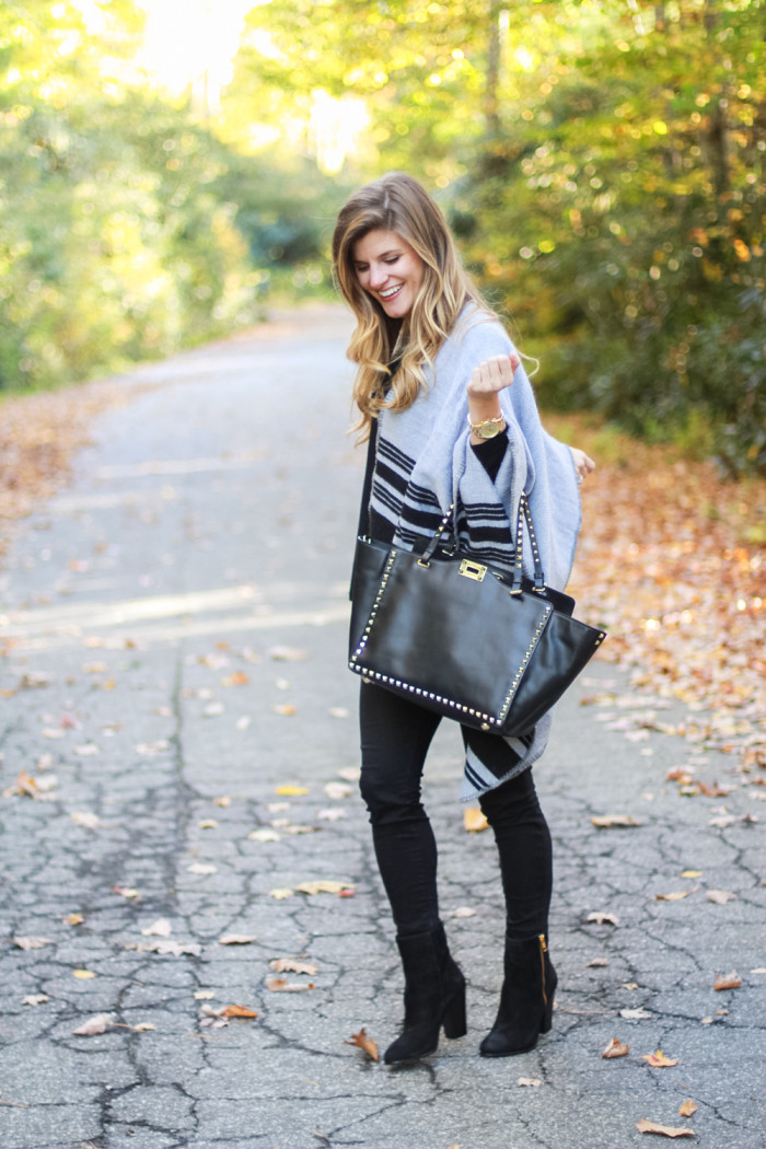 grey poncho over all black outfit and black leather Valentino bag