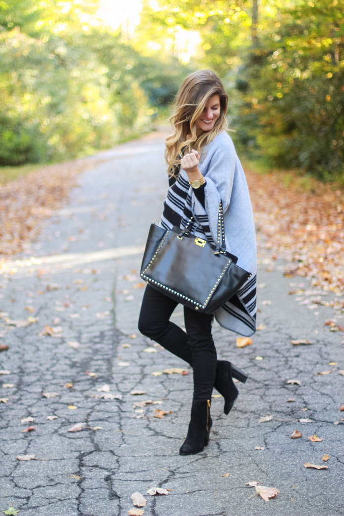 grey poncho and black turtleneck with black pants and black booties and black valentino bag
