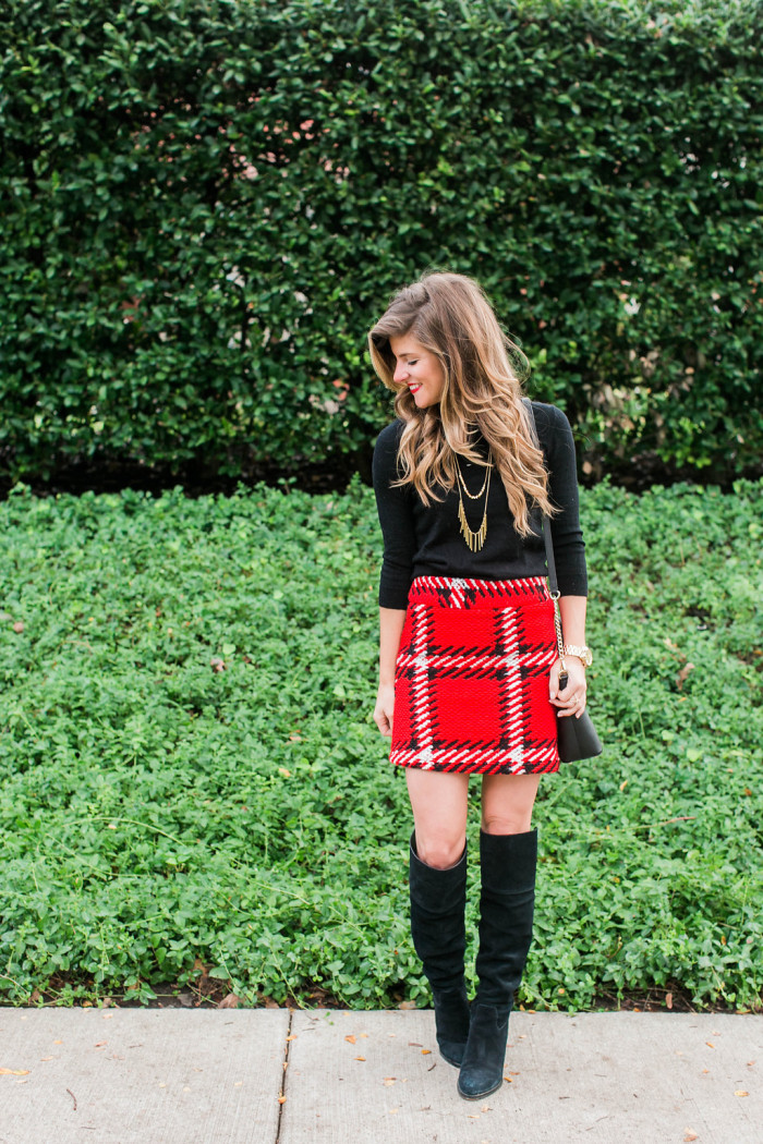 Red black plaid mini skirt with black tall boots, black sweater, gold necklace, kate spade crossbody holiday outfit 