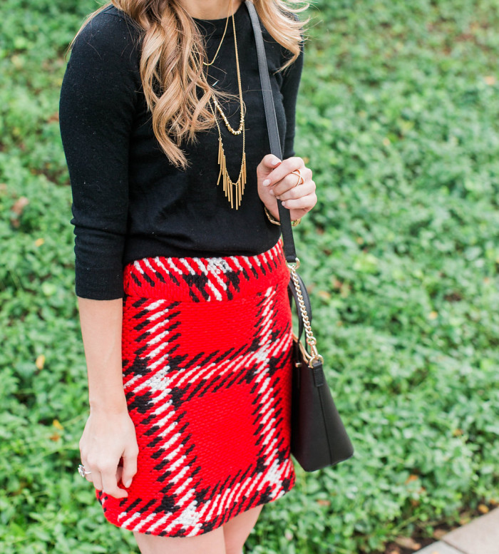 Red black plaid mini skirt with black sweater, gold necklace, kate spade crossbody holiday outfit 