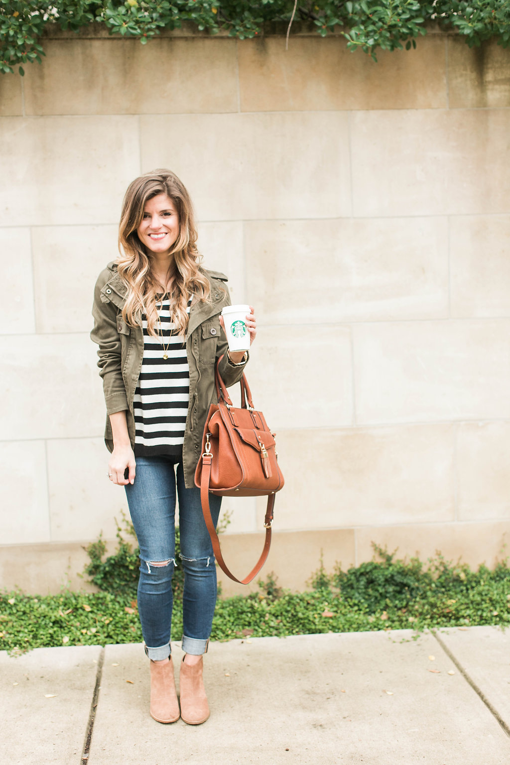 cute fall outfit idea, how to wear a green military jacket styled with black and white stripes,cognac booties and brown leather sole society bag