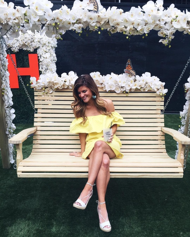 @brightonkeller sitting on bench swing at Joe Fresh Garden party wearing yellow off the shoulder dress with white wedges
