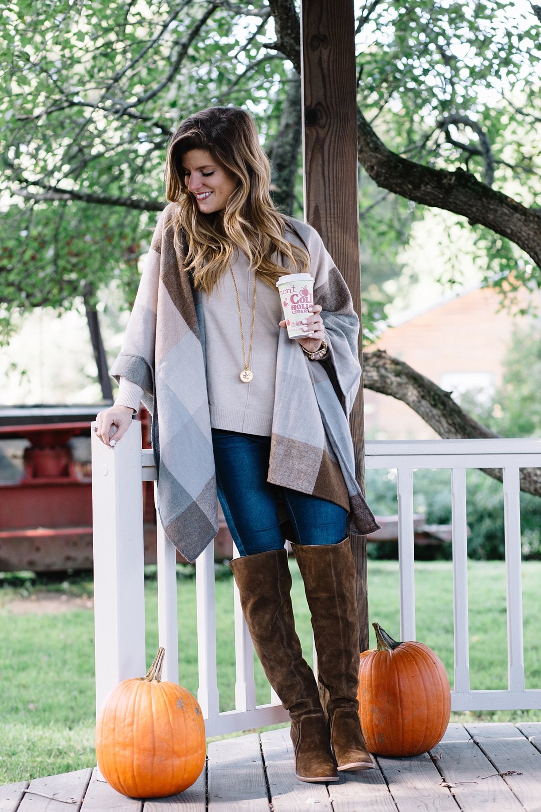 brighton the day at cold hollow cider mill drinking hot apple cider and wearing nordstrom poncho with brown tall boots and jeans for cute fall outfit 