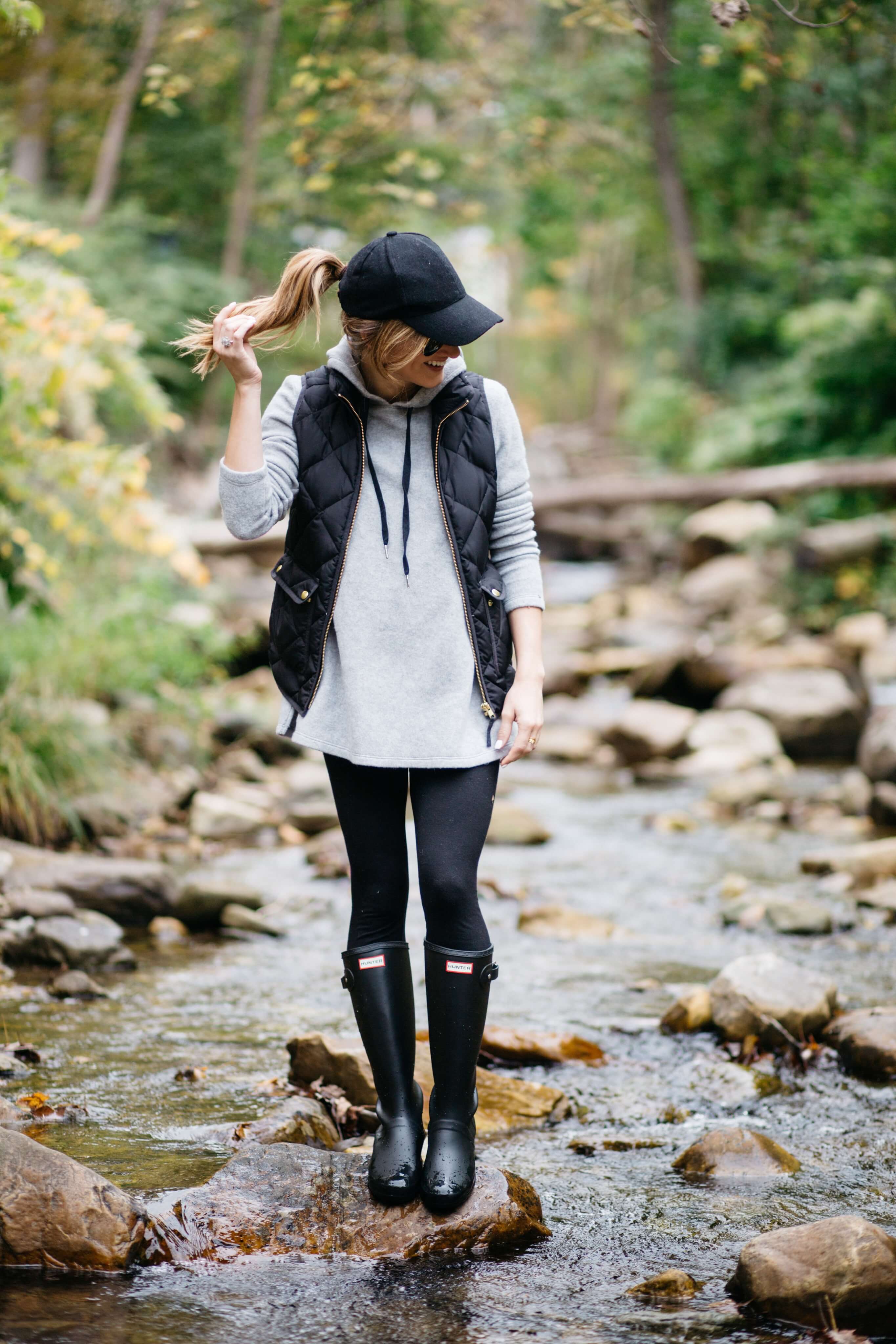 how to wear leggings - wear leggings on a rainy day, rain day outfit with hunter boots, hoodie, puffer vest, baseball cap, black hunter boots