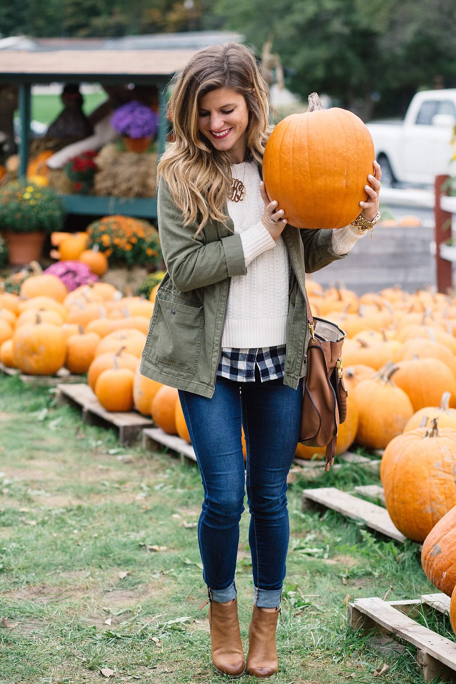 fall outfit, olive green military jacket, cable knit sweater with gingham shirt underneath, layered sweater and gingham button up shirt, rolled up jeans and booties, jeans and booties, utility jacket outfit, cognac ankle booties, monogram necklace, chloe ran bag, cute fall casual outfit
