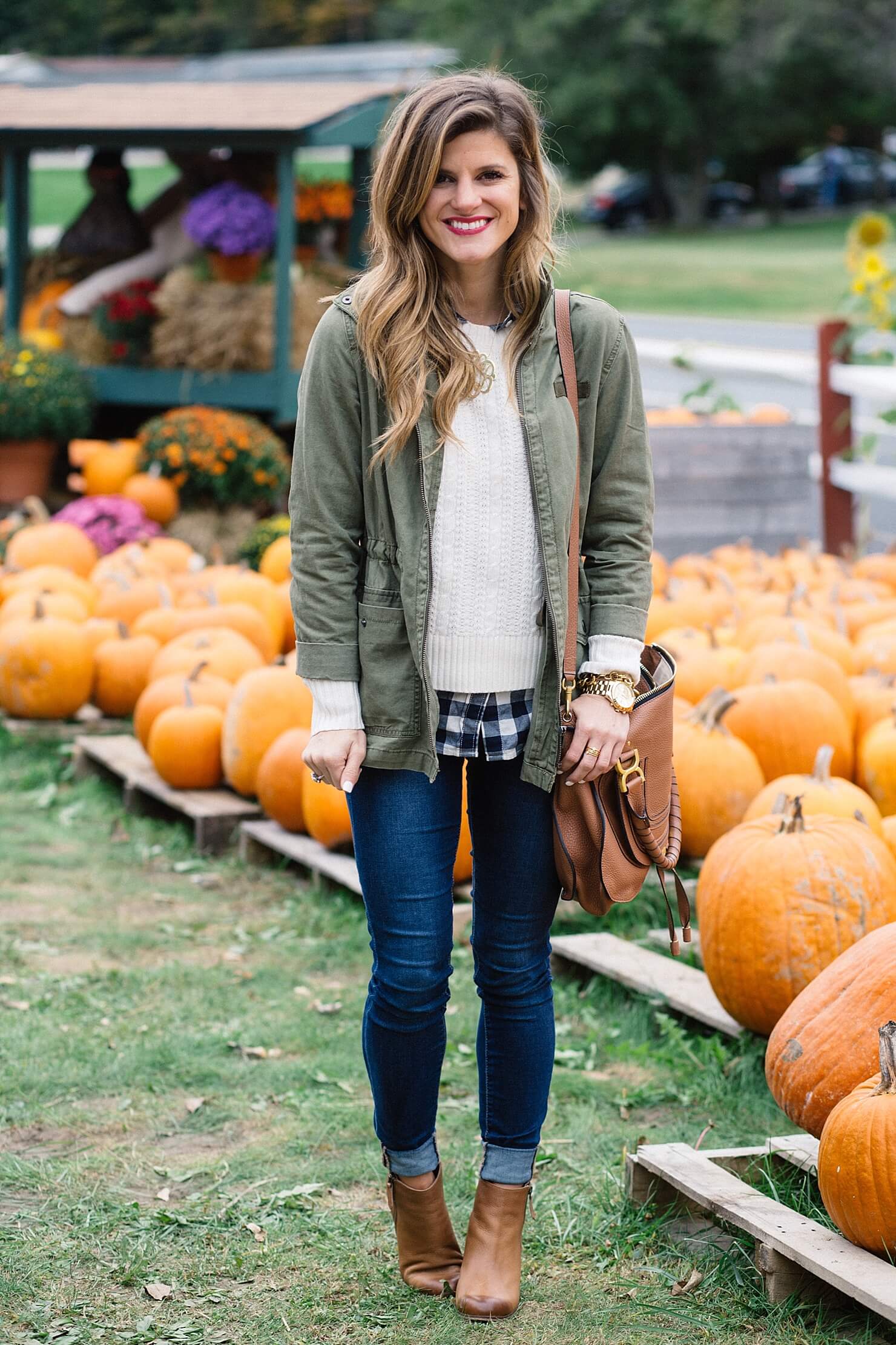 fall outfit, olive green military jacket, cable knit sweater with gingham shirt underneath, layered sweater and gingham button up shirt, rolled up jeans and booties, jeans and booties, utility jacket outfit, cognac ankle booties, monogram necklace, chloe ran bag, cute fall casual outfit