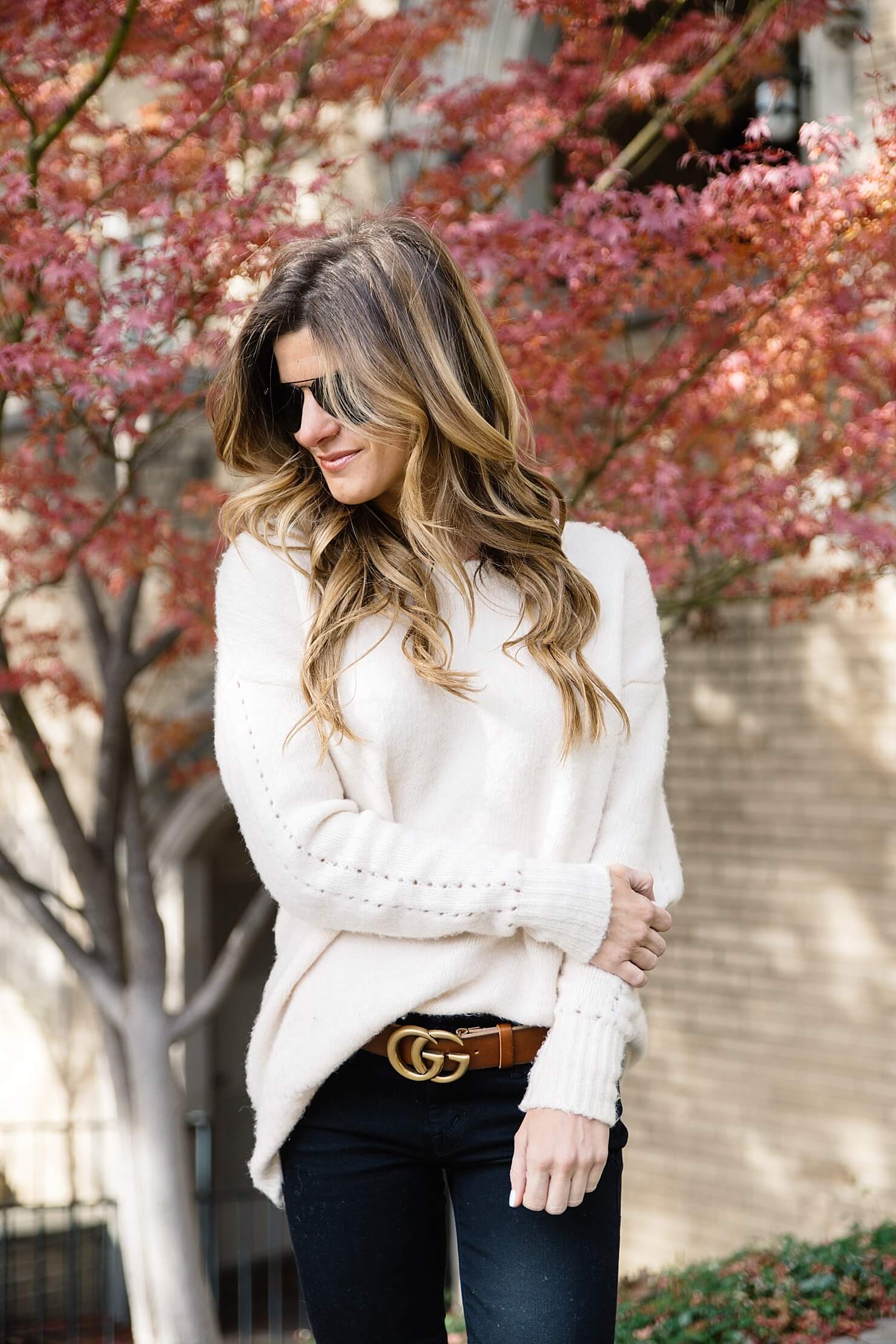oversized cream sweater, brown and gold statement gucci logo belt, all black aviators, black jeans and brown belt
