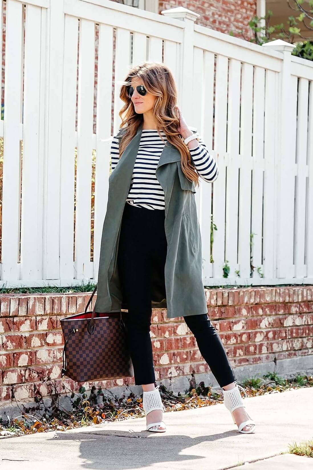 green trench vest, striped tee, black pants, business casual outfit idea, longline sleeveless jacket, black work pants outfit
