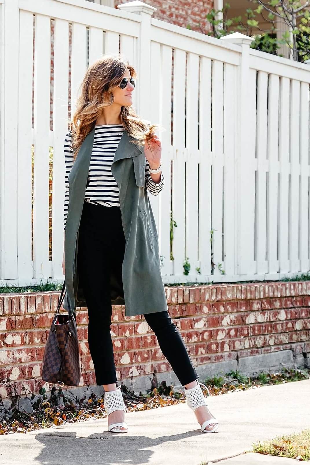 green trench vest, striped tee, black pants, business casual outfit idea, longline sleeveless jacket, black work pants outfit