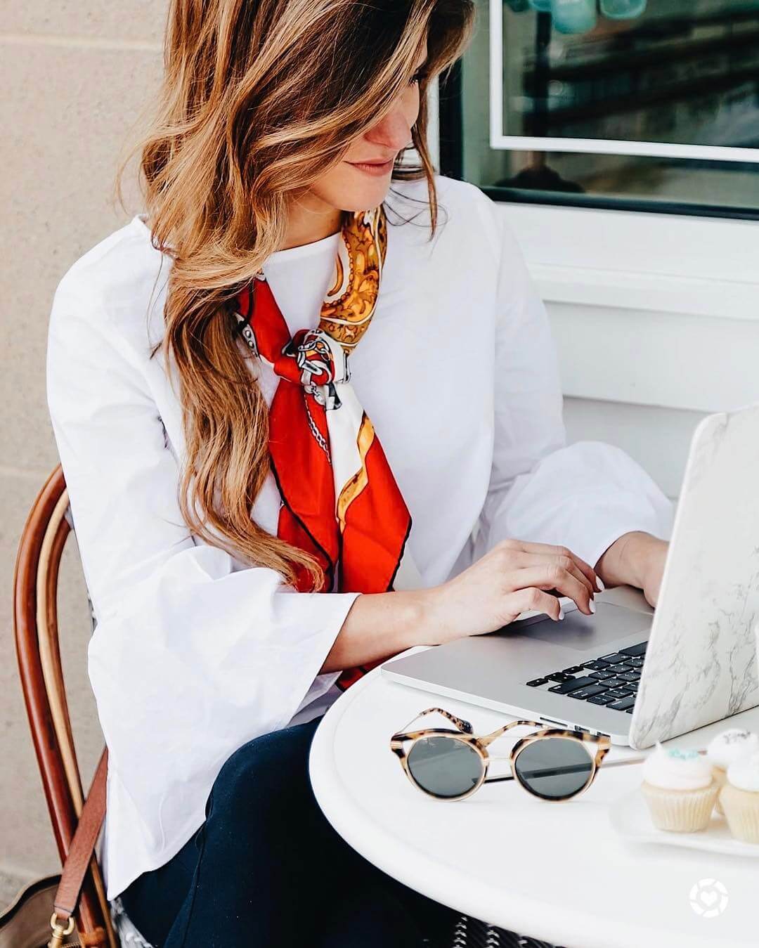 brighton keller at Bird Bakery Dallas wearing white blouse, neck scarf, and sonic sunglasses 