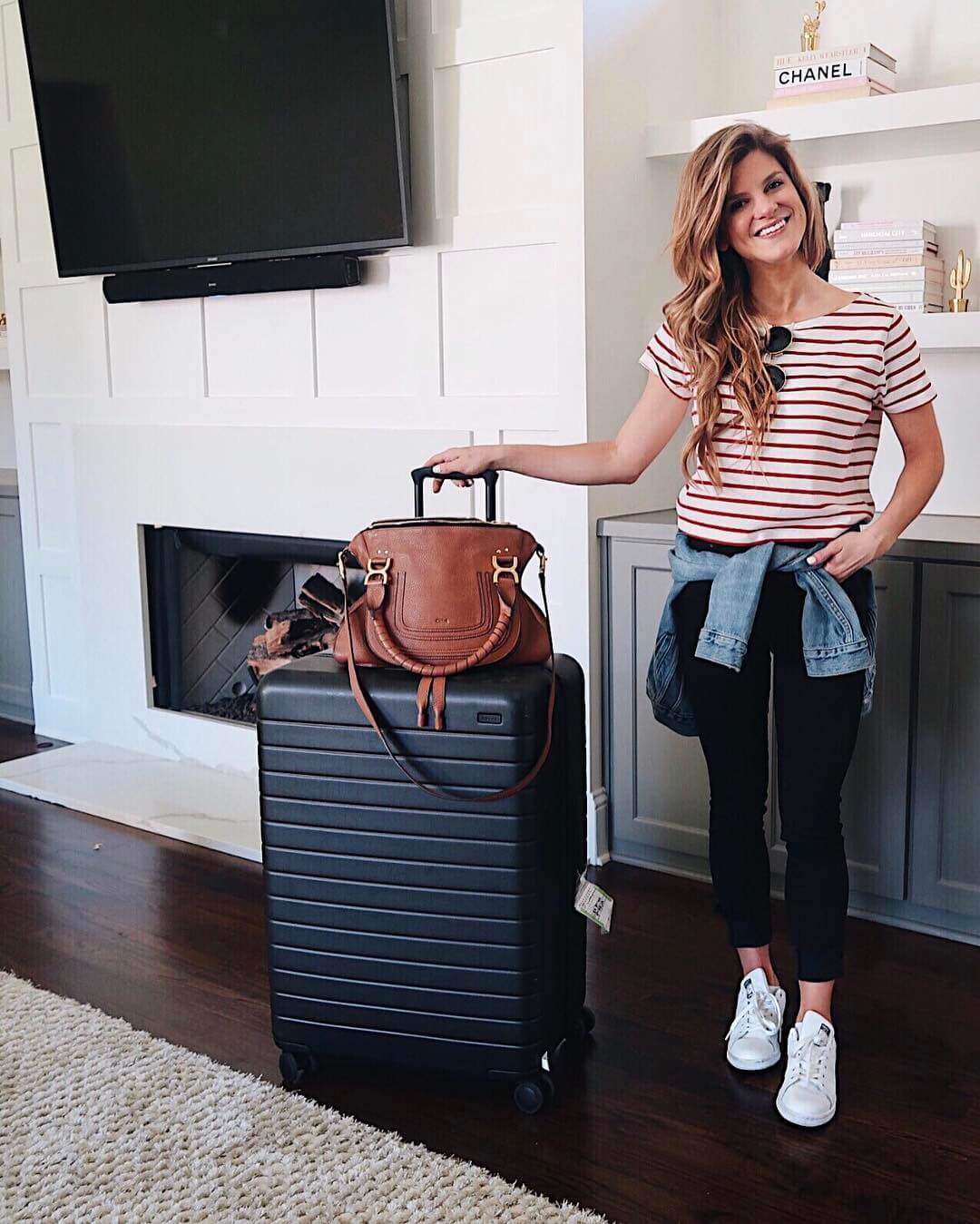 brighton keller travel outfit ideas wearing red and white striped tee with black jeans and denim jacket 