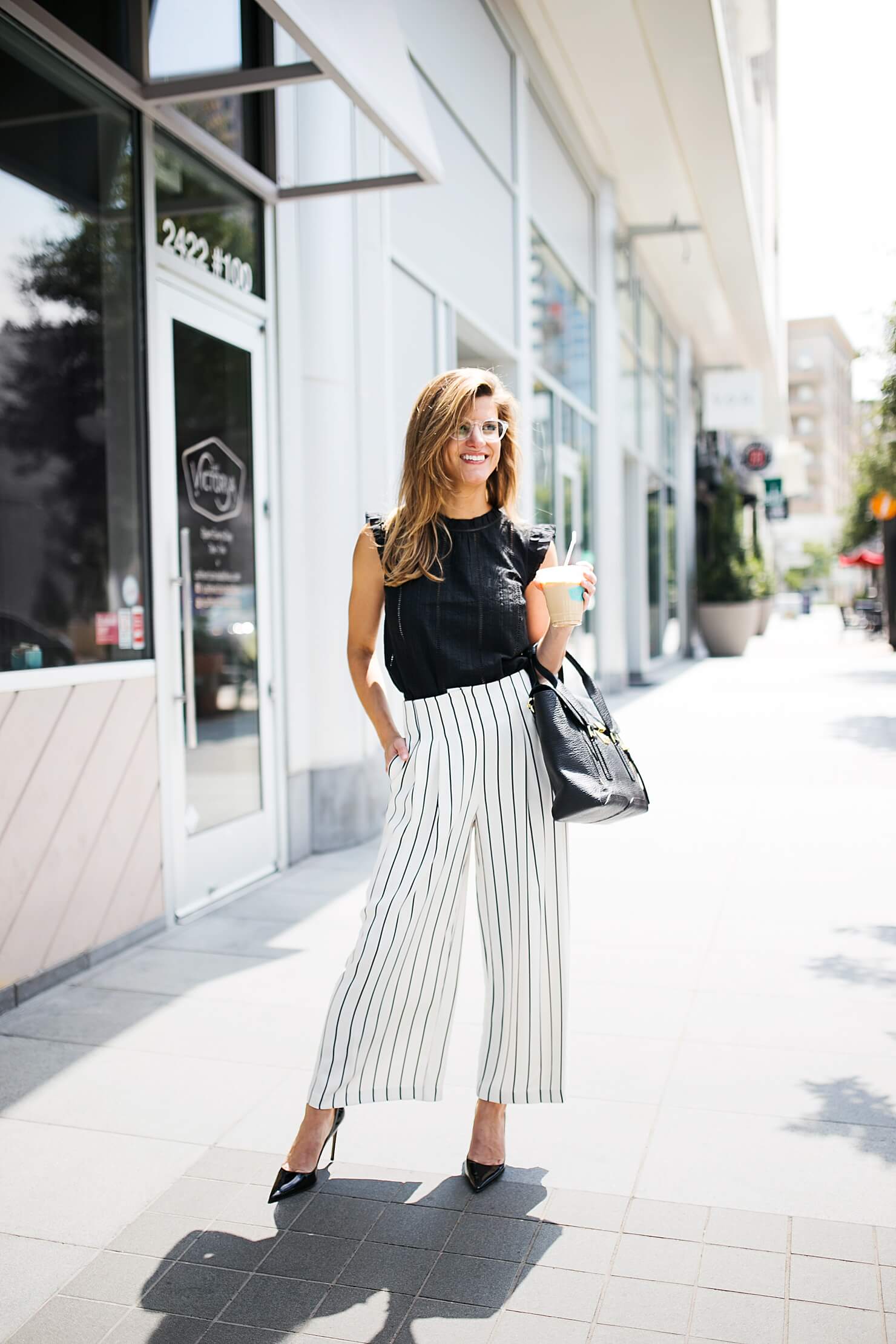 brighton keller wearing eyelet black top with striped culottes, wide leg pants and pumps 