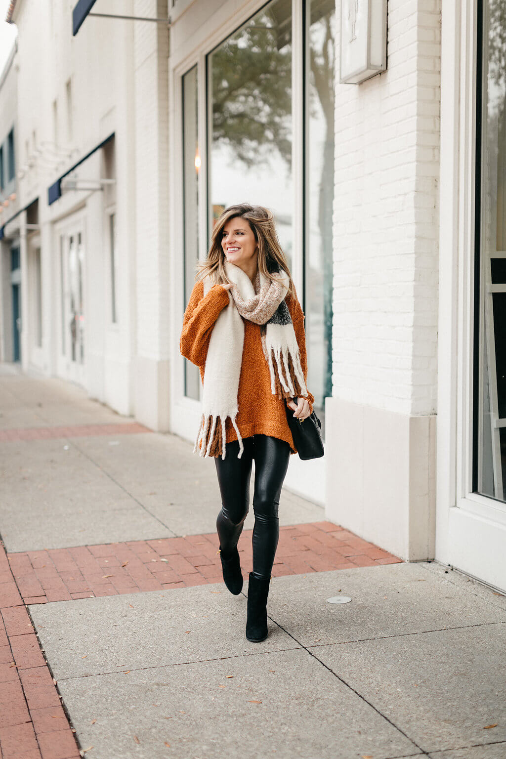 leather leggings, orange sweater, and oversized scarf