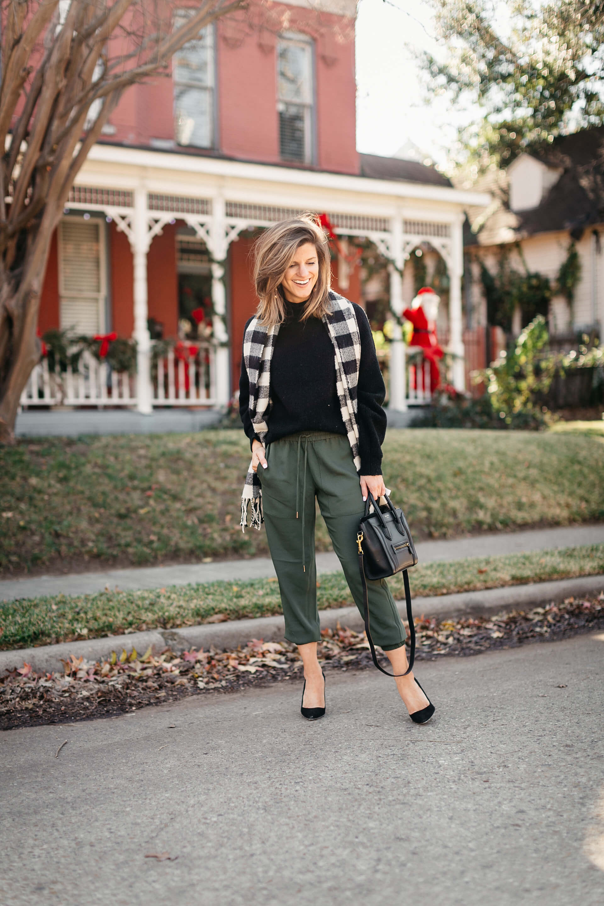 green joggers, black sweater, checkered scarf and cap