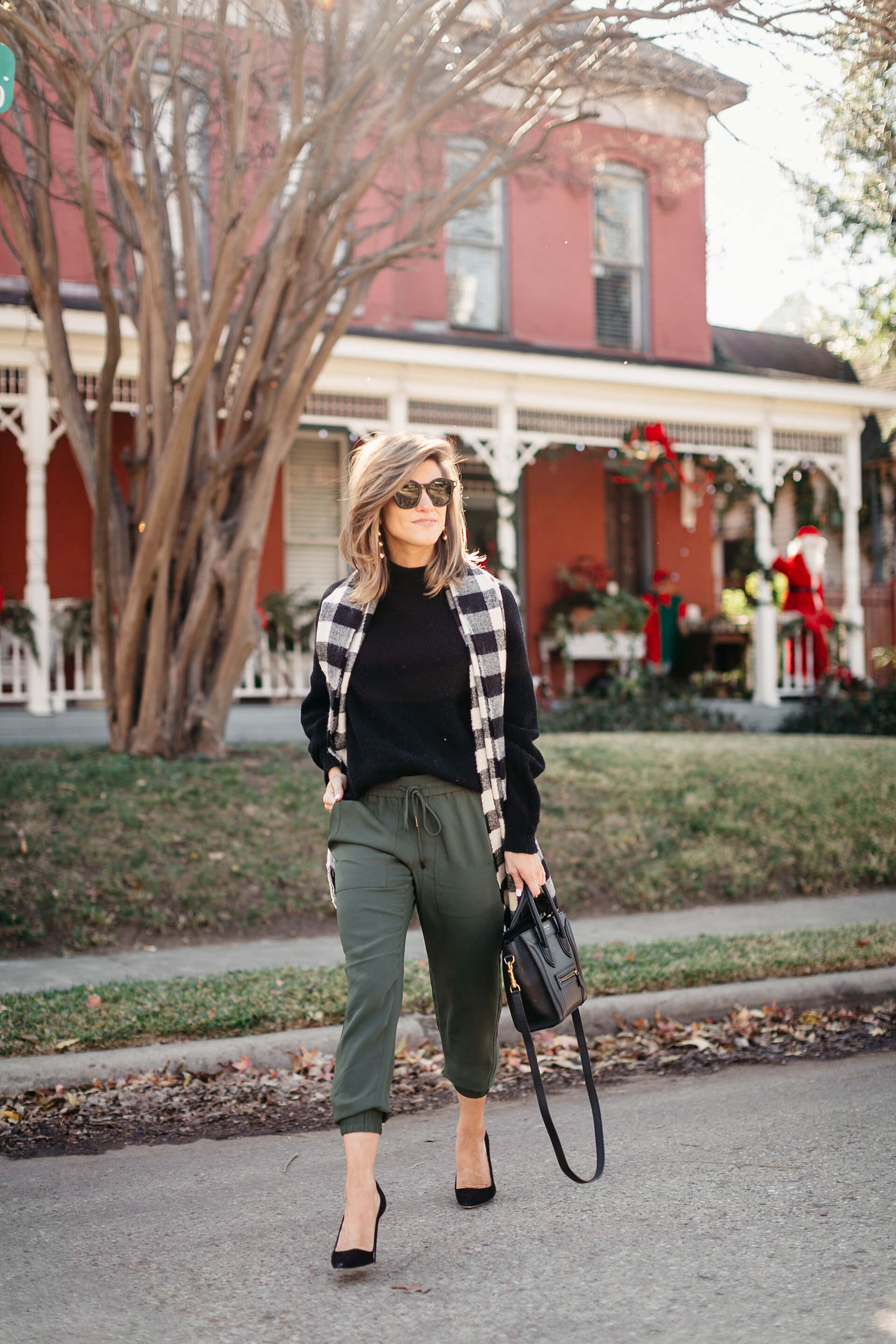 green joggers, black sweater, checkered scarf and cap