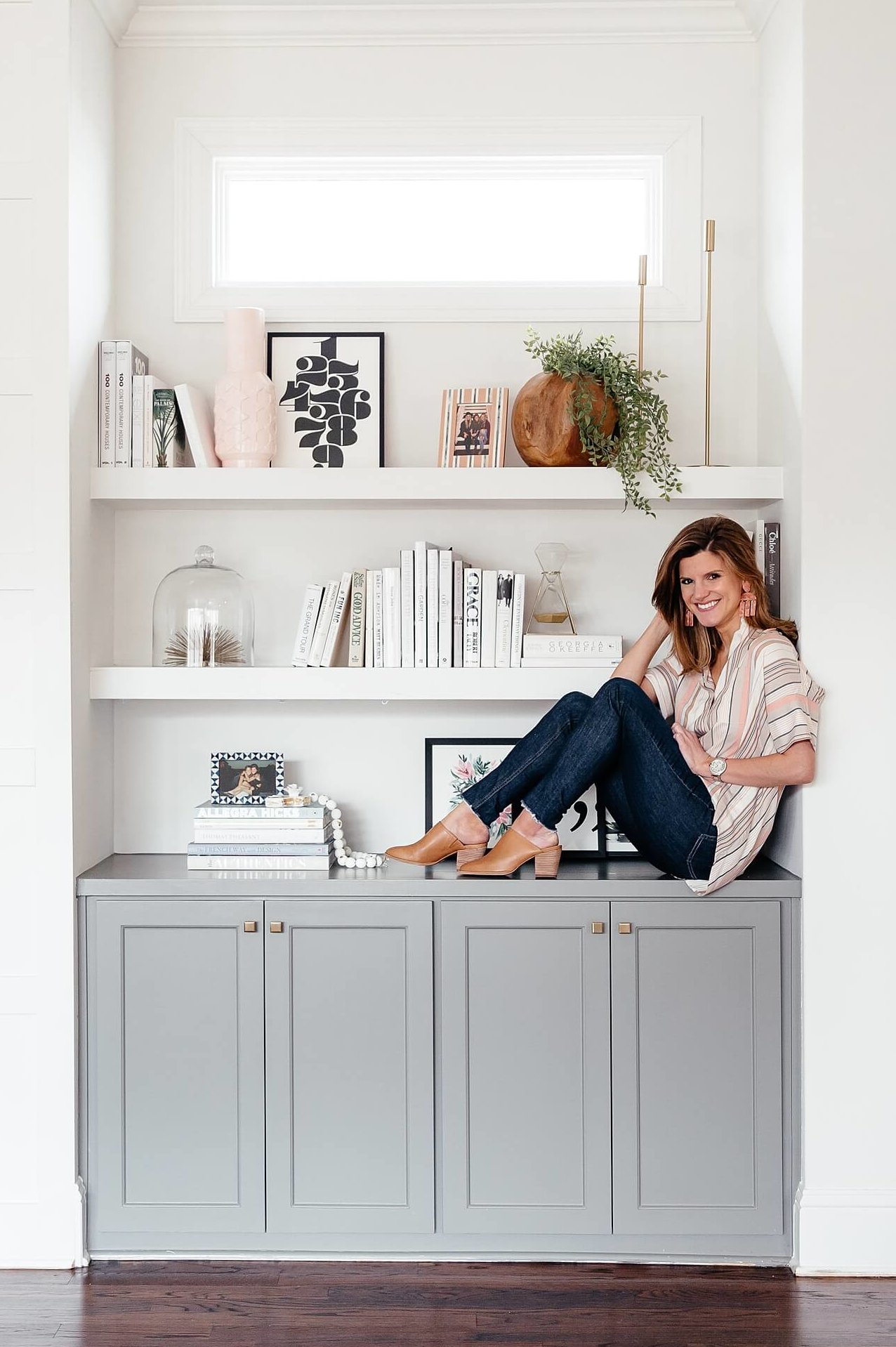 brighton keller sitting on living room bookshelves, Sherwin Williams Chelsea Grey Paint color on cabinets