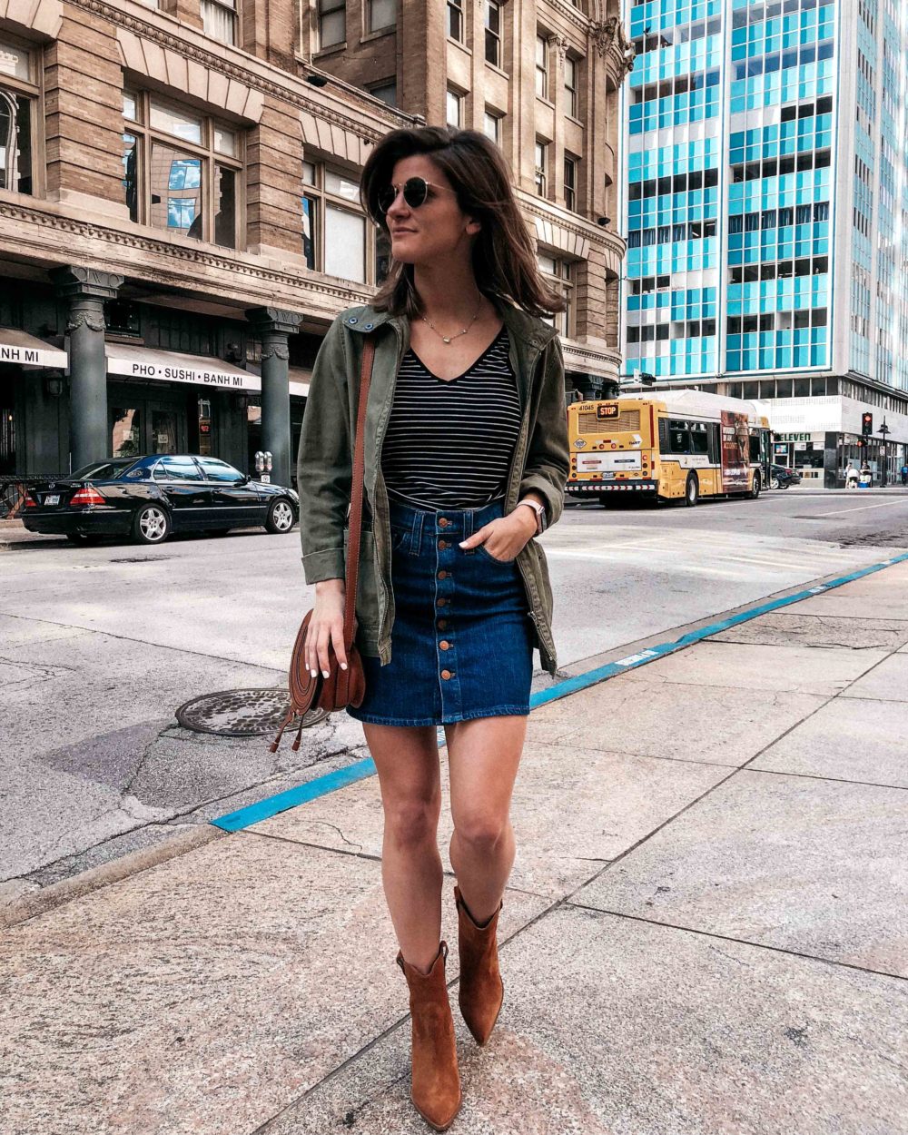 miltiary jacket outfit with denim skirt, striped tank, and booties