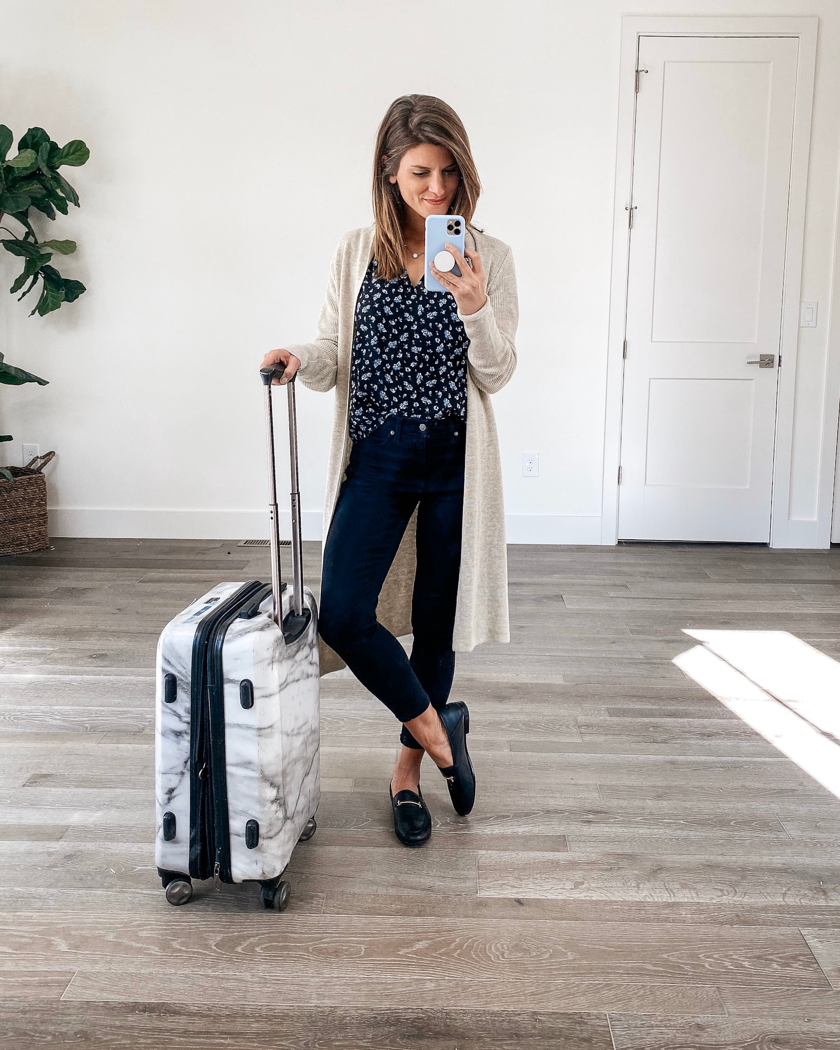 brighton keller wearing travel outfit with loafers and jeans and cami and cardigan