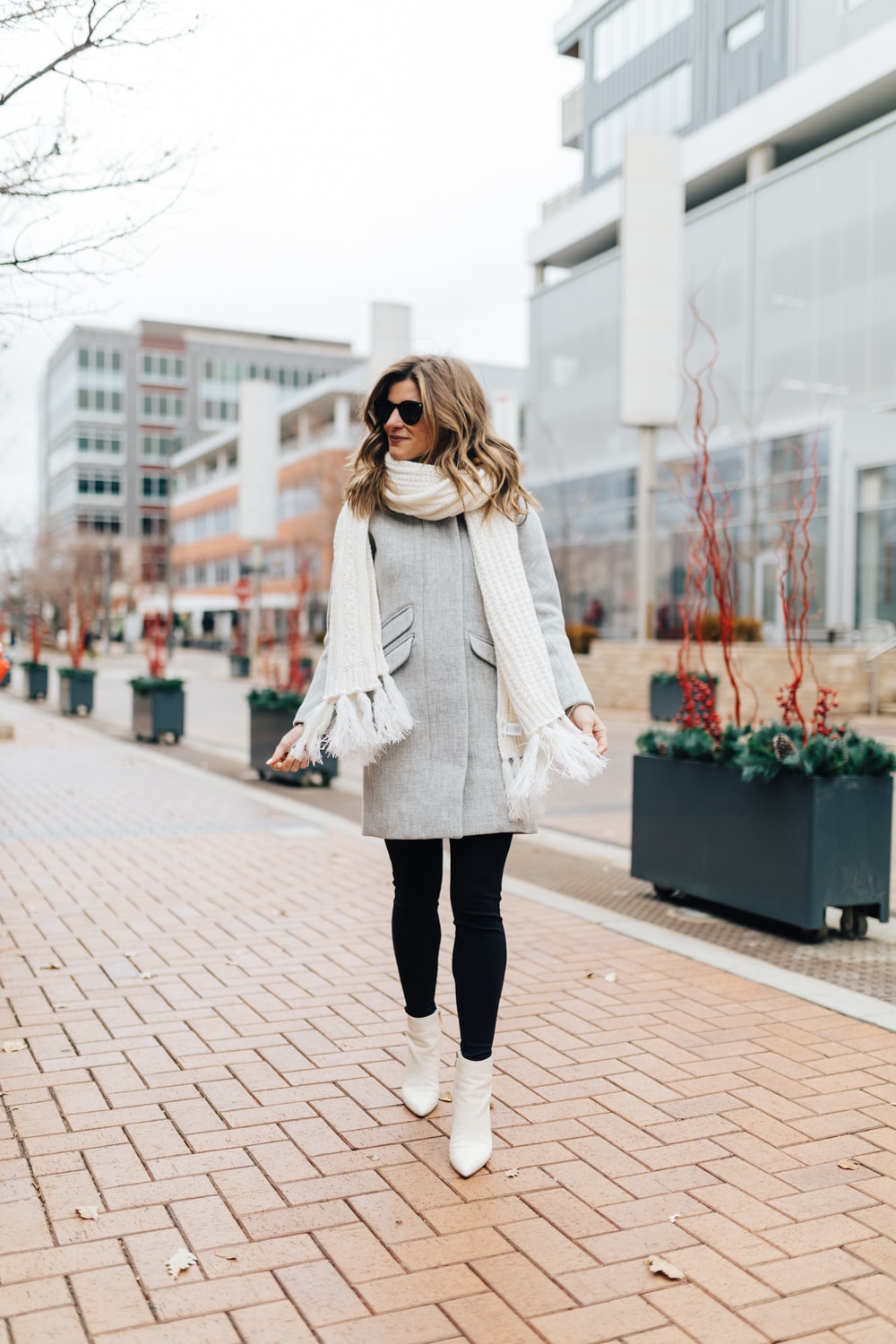 winter outfit idea grey coat, black jeans, white booties cozy scarf