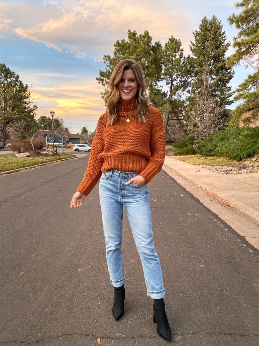brighton keller wearing rust sweater mom jeans and booties