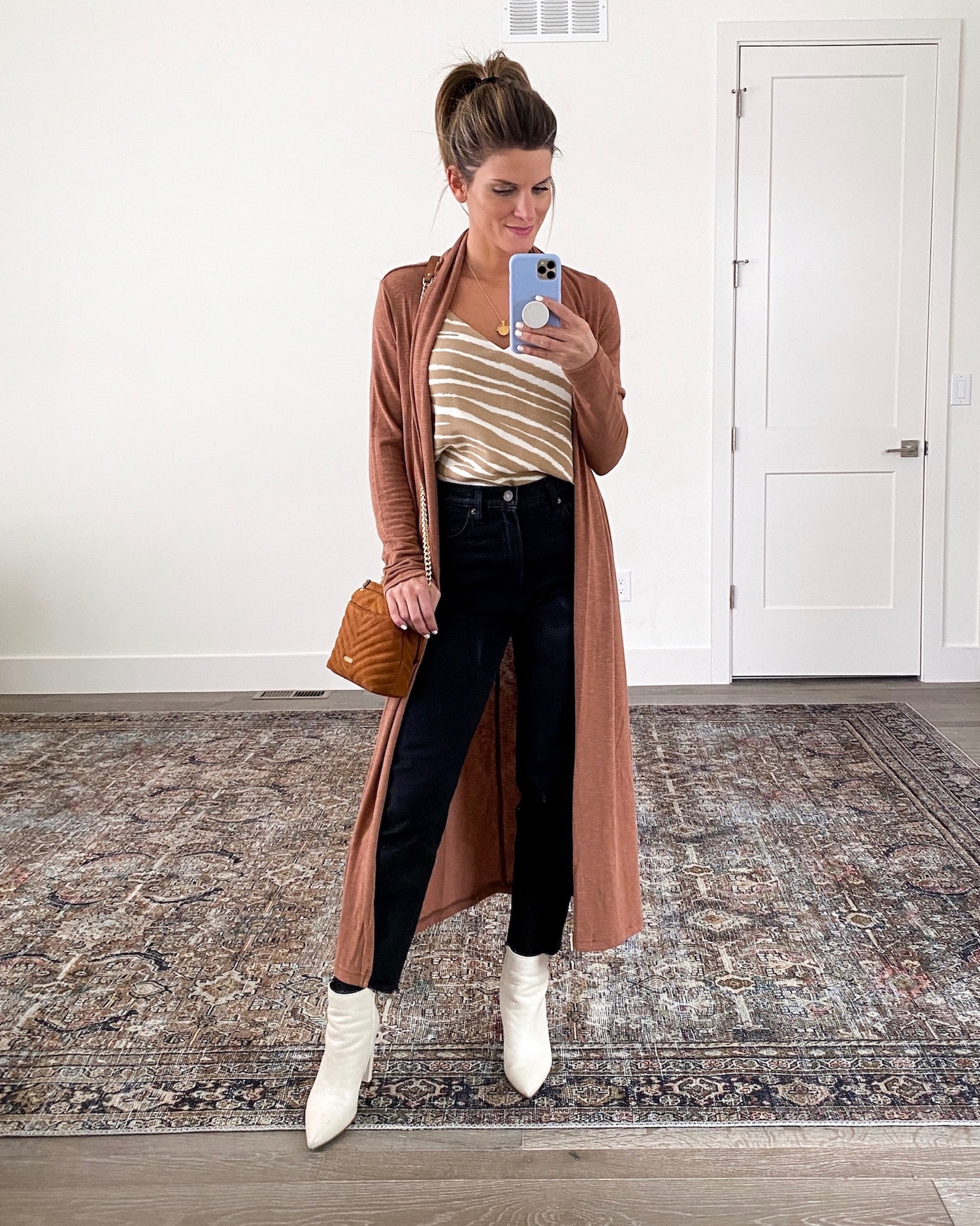 Brighton Keller wearing striped came, black jeans, duster and white booties