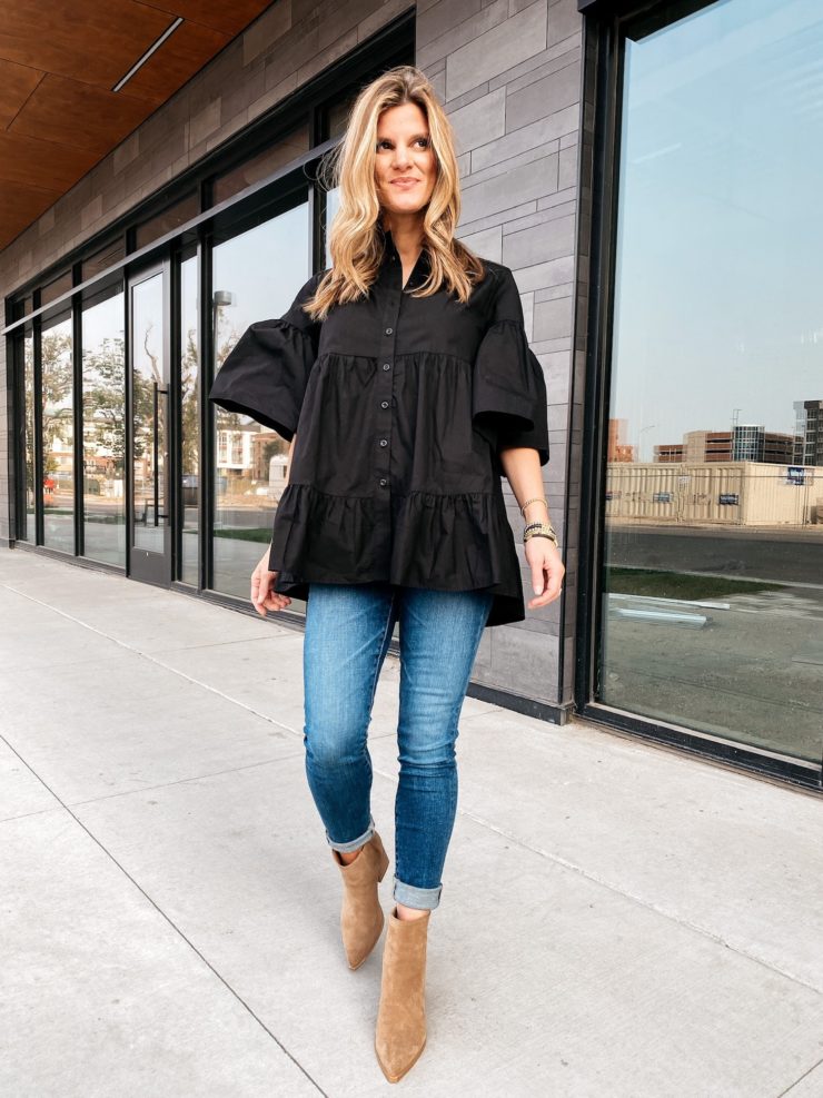 Brighton Butler wearing a black tunic top, jeans and brown booties