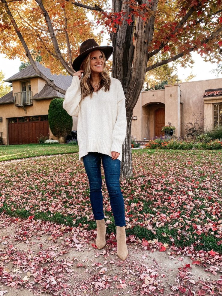 Brighton Butler wearing a white tunic seater, jeans, brown hat and tan booties