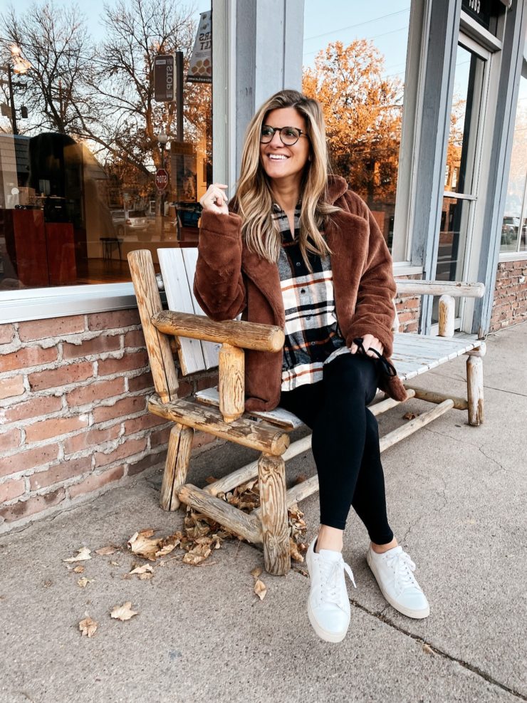 Brighton Butler wearing a plaid top, brown fur jacket, black jeans and sneakers