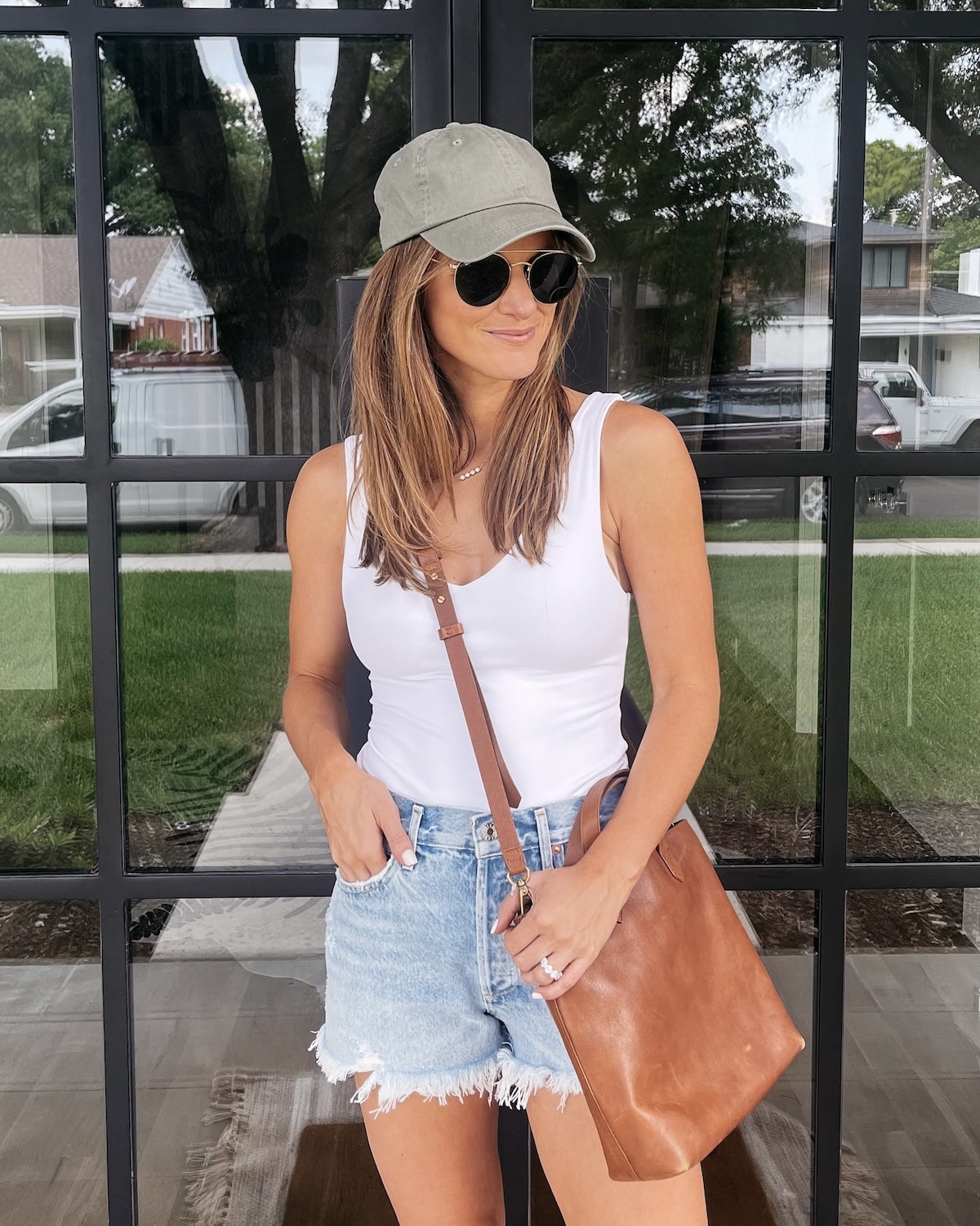 Brighton Butler wearing white bodysuit with jean shorts and ball cap, how to style a bodysuit