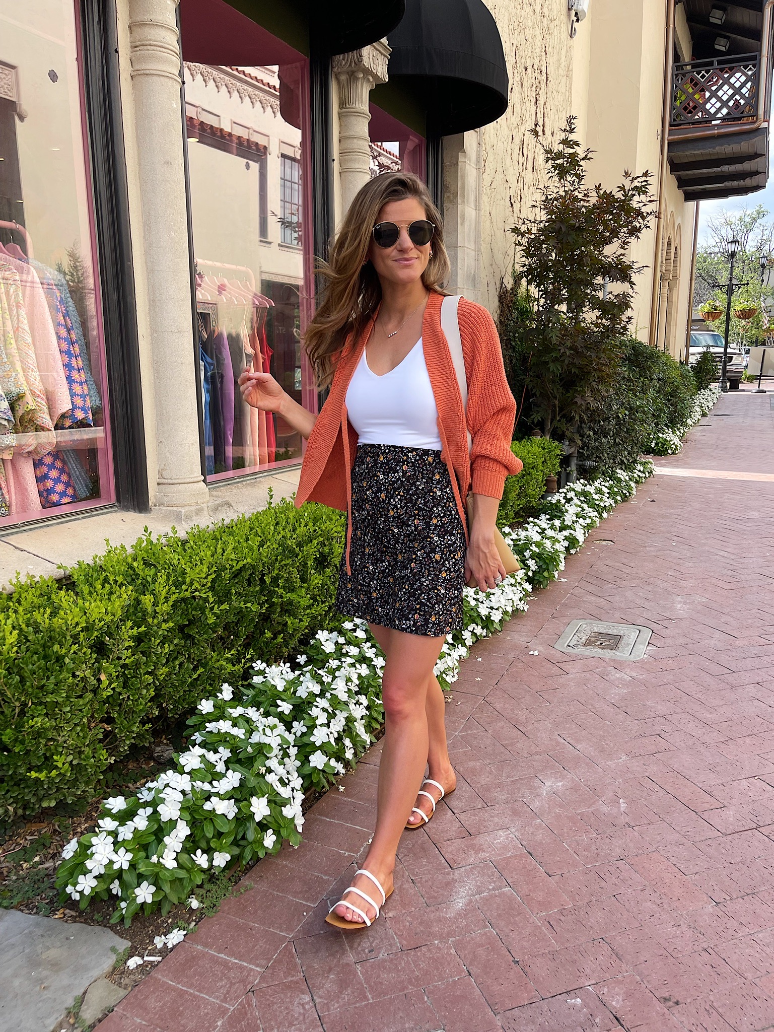 Brighton Butler wearing made well mini slip skirt in folkmagic floral, made well eastdale tie front cardigan sweater in orange, Abercrombie double layer seamless v neck bodysuit in white