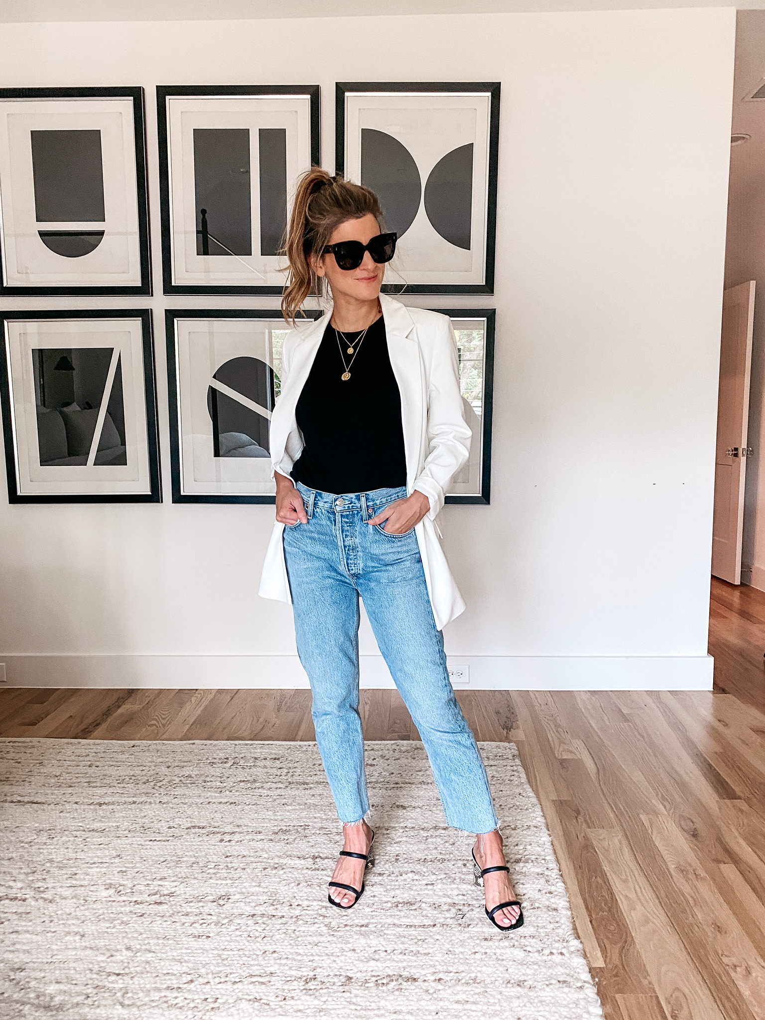 Brighton Butler wearing white blazer, black tee and light wash jeans with sunglasses