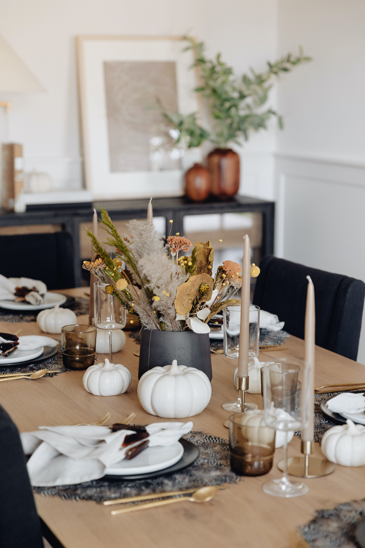Brighton Butler Fall Tablescape with black and white plates, taupe candles, gold candlestick, dried flower arrangement centerpiece