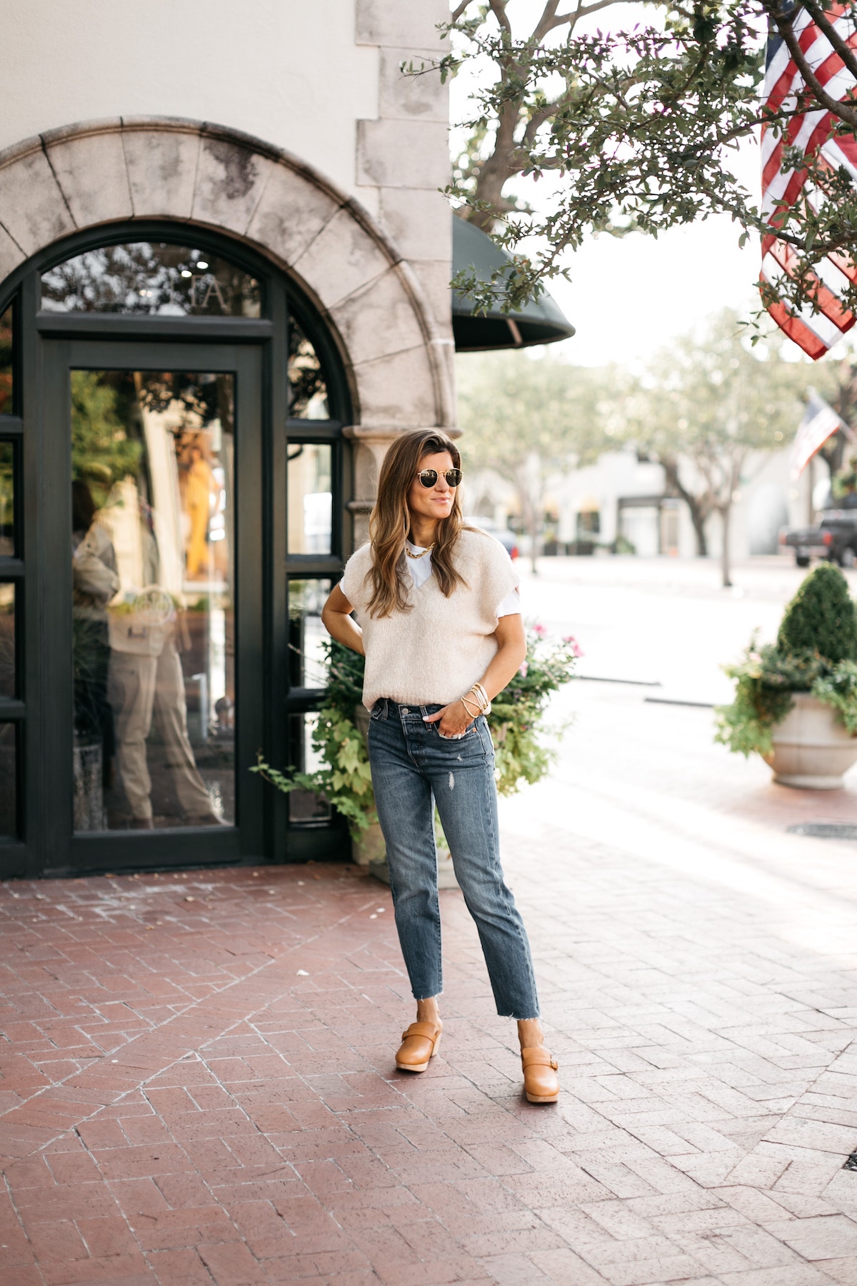 Brighton Butler wearing sweater vest layered over white tee, Levi's denim, clogs, sweater vest trend