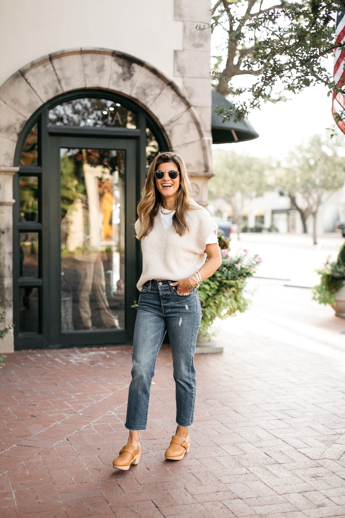 Brighton Butler wearing sweater vest layered over white tee, Levi's denim, clogs, sweater vest trend
