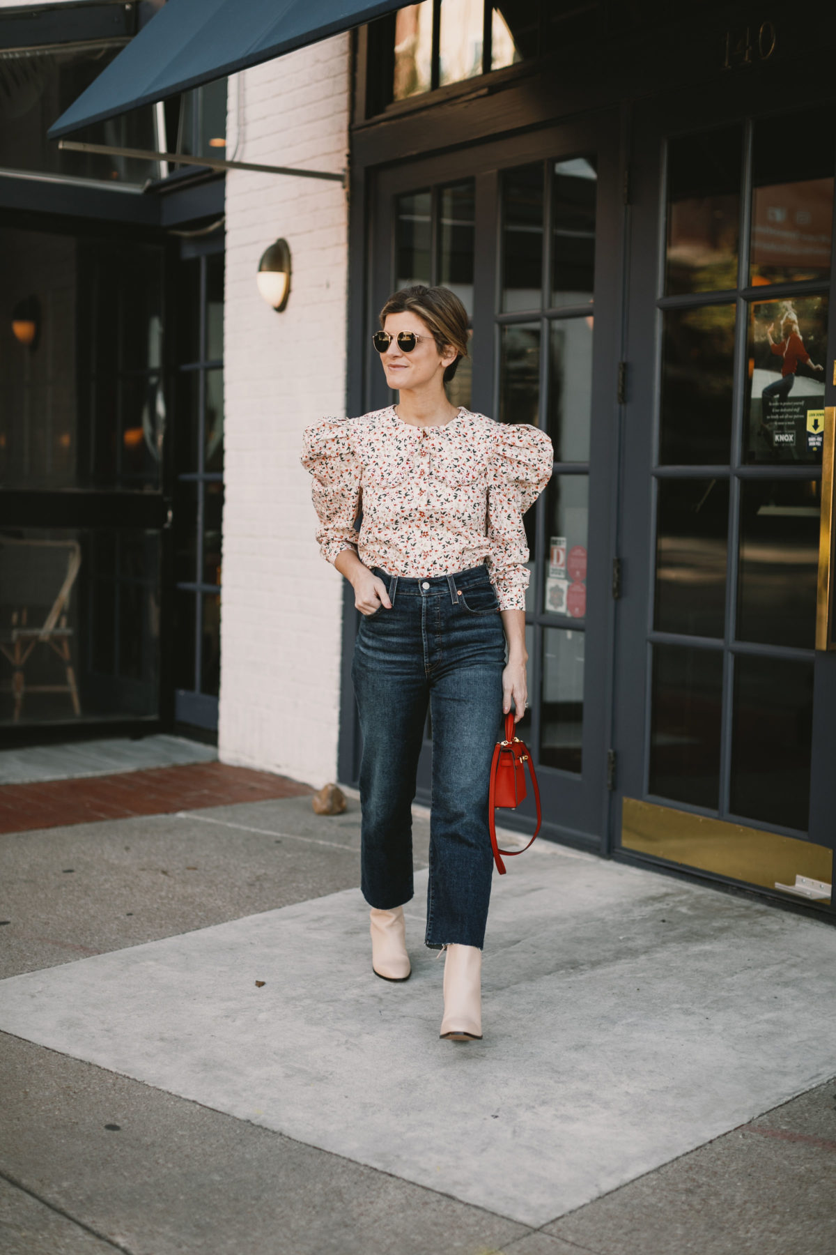 brighton butler weraing high-waisted jeans with floral top and booties