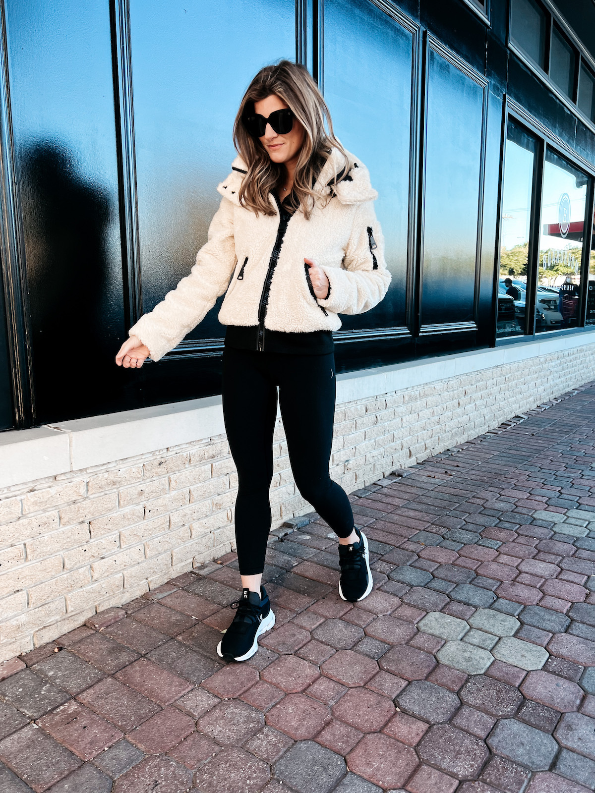 Brighton Butler wearing Backcountry sherpa jacket with black leggings and on cloud sneakers
