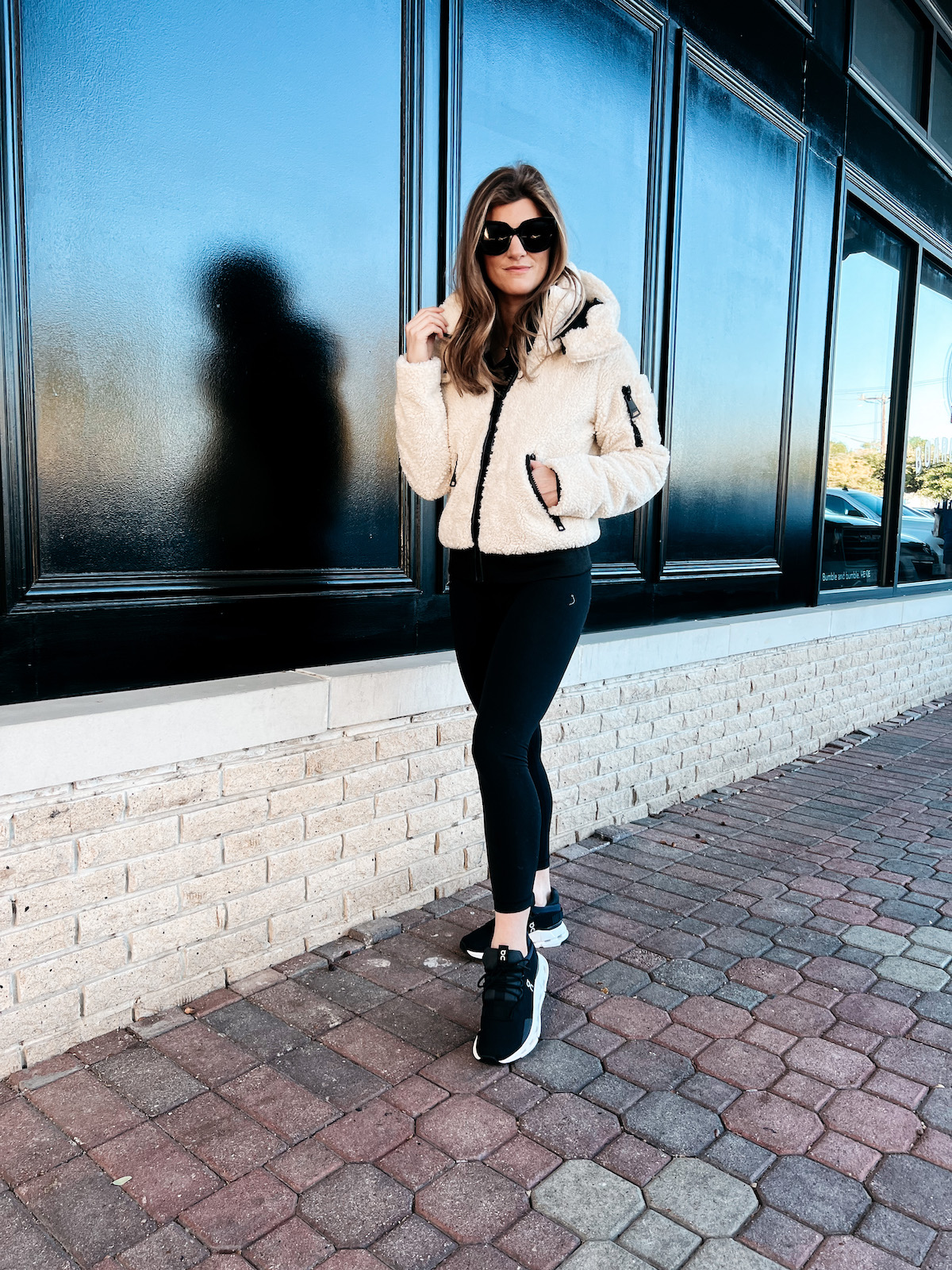 Brighton Butler wearing Backcountry sherpa jacket with black leggings and on cloud sneakers