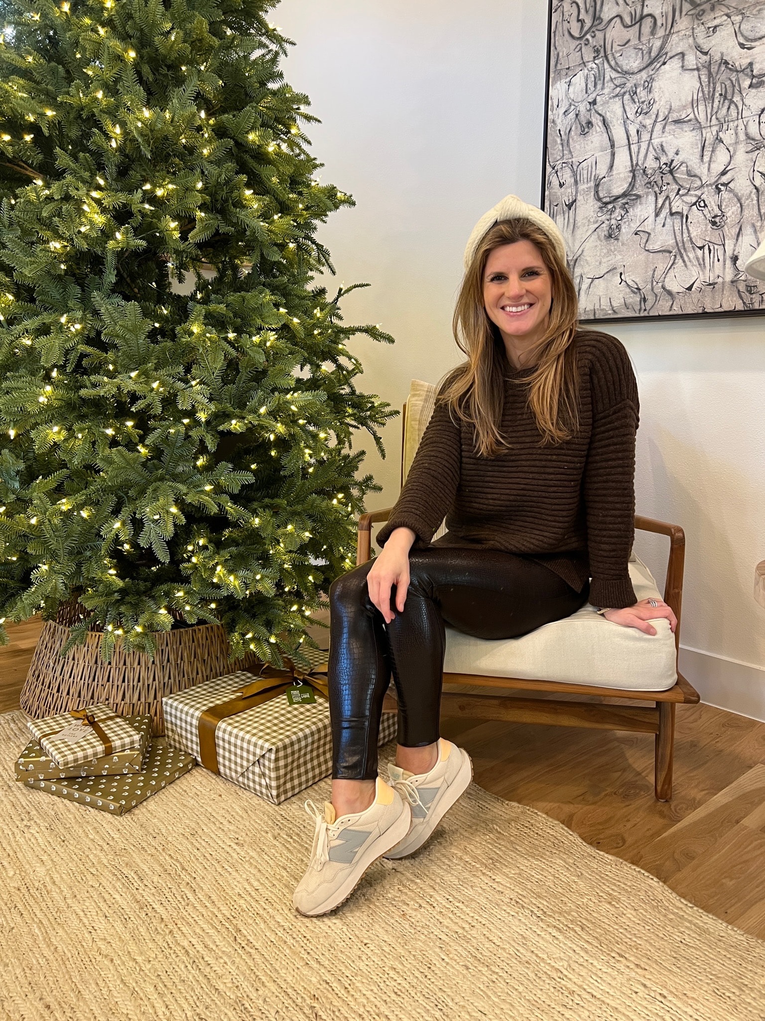Brighton Butler in striped sweater, leather leggings and sneakers by Christmas tree