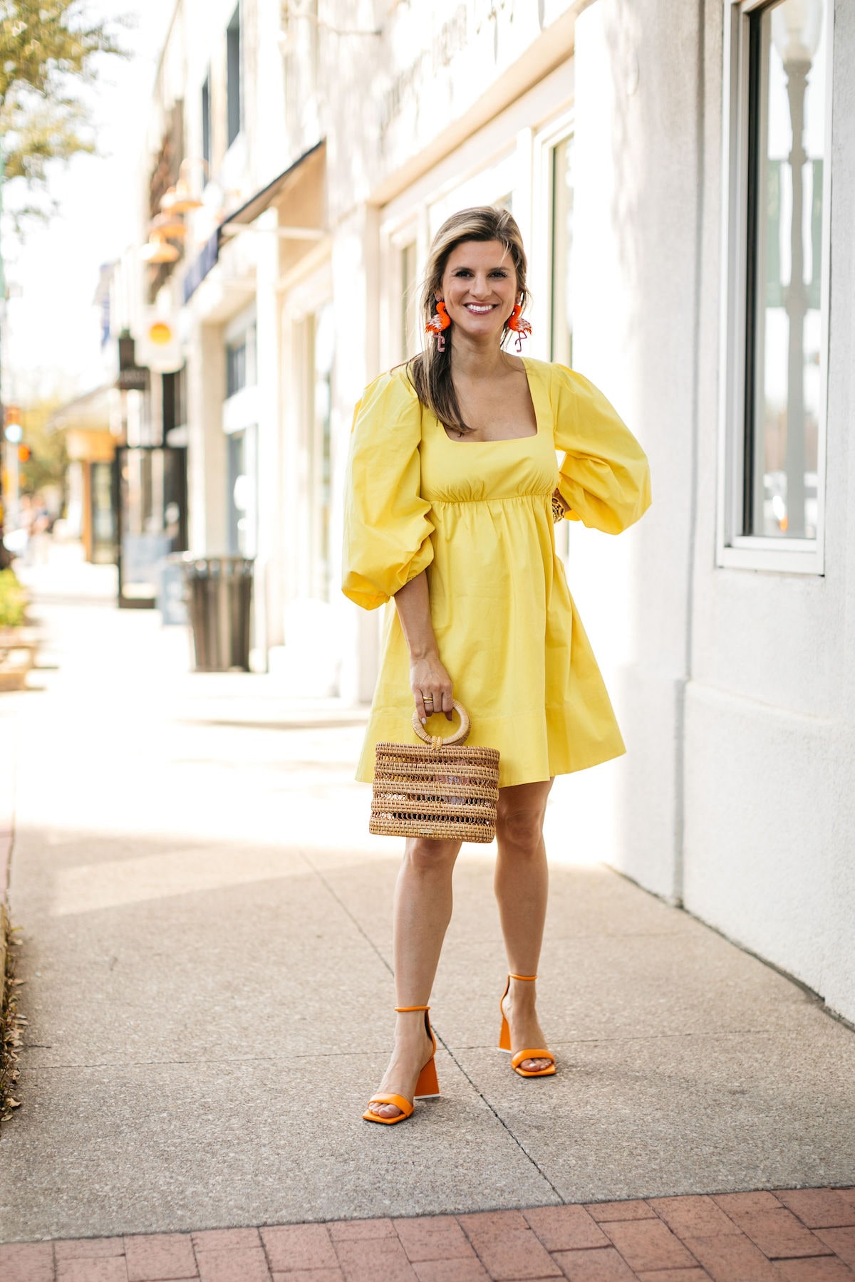 Brighton Butler wearing staud yellow dress with flamingo earrings and cult gaia bag